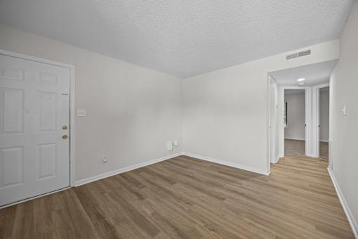 A white painted room with a white door and wooden flooring.