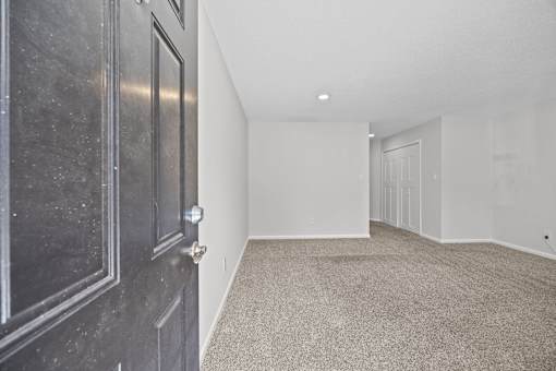 Enter the front door painted black with carpeted floor and white walls.