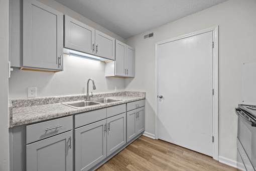 A kitchen with grey cabinets and a kitchen sink.