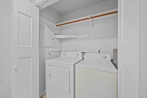 A white laundry room with open doors to the washer and dryer.