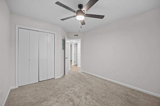 Bedroom with a ceiling fan and carpeted floor plus a closet.