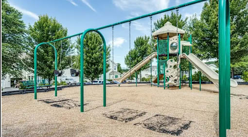 A playground with a green slide and a tower.