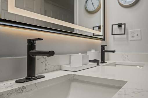 A modern bathroom with a marble countertop and a large mirror above the sink.