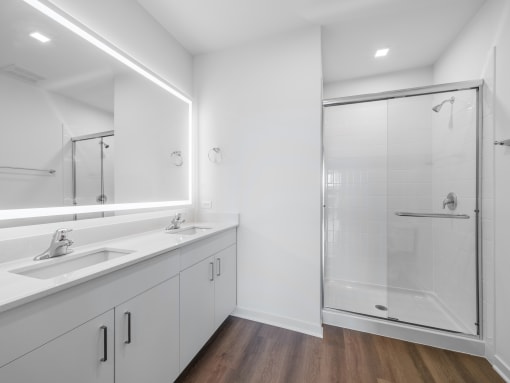 a white bathroom with two sinks and a shower