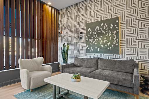 A living room with a grey couch, a white coffee table, and a painting on the wall.