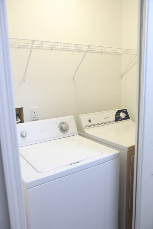 a white washer and dryer in a white laundry room with white walls at Evergreen Luxury Apartments, Merrillville, 46410