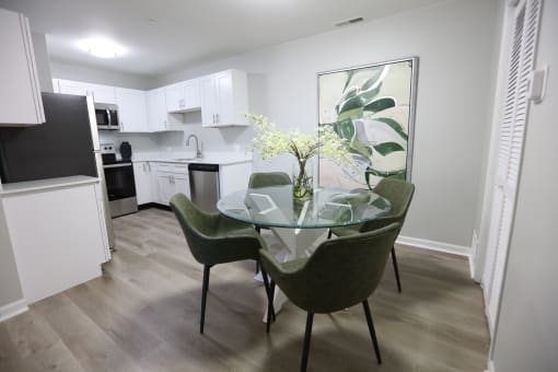 a kitchen and dining room with a glass table and chairs at Evergreen Luxury Apartments, Merrillville, IN