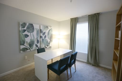 a dining room with a white table and chairs and a painting on the wall at Evergreen Luxury Apartments, Merrillville, Indiana