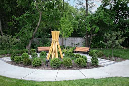 a garden with benches and a sculpture in the middle