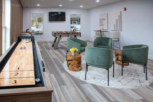 A pool table with numbered pockets is in the middle of a room with a green chair and a TV at Evergreen Luxury Apartments, Merrillville, Indiana