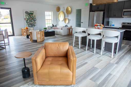 A living room with a tan leather chair and a grey floor at Evergreen Luxury Apartments, Merrillville, IN