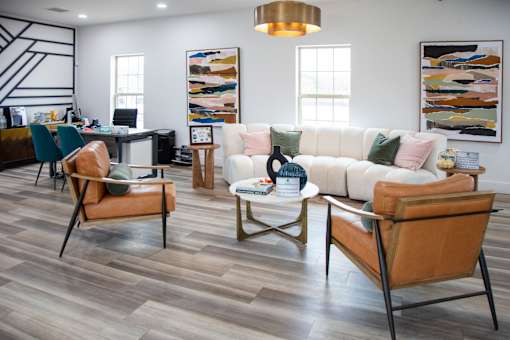 A living room with a white couch and brown chairs at Evergreen Luxury Apartments, Merrillville, Indiana