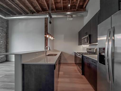 A modern kitchen with stainless steel appliances and wooden floors.