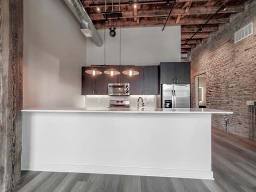 A modern kitchen with a white countertop and wooden beams on the ceiling.