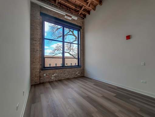 A room with a large window and wooden flooring.