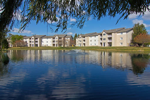 a fountain in the middle of a lake in front of an apartment building at Evergreen Luxury Apartments, Merrillville, 46410