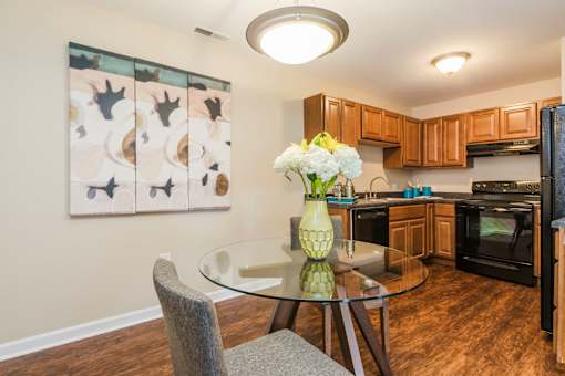 A kitchen with a table and chairs and a painting on the wall at Evergreen Luxury Apartments, Merrillville, IN