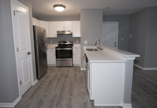 a kitchen with white cabinets and stainless steel appliances at Evergreen Luxury Apartments, Indiana