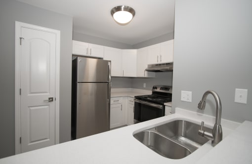 a kitchen with white cabinets and stainless steel appliances at Evergreen Luxury Apartments, Merrillville, Indiana