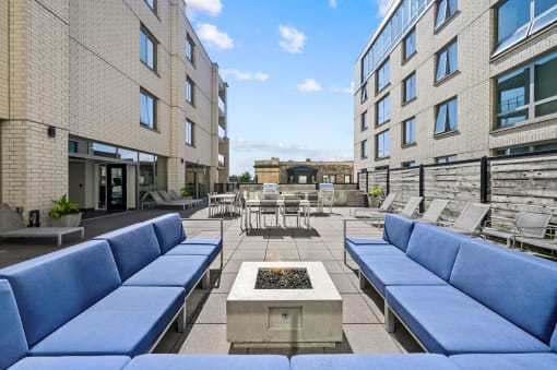 a seating area with couches and chairs on a patio with a fire pit in the middle at Lakeview 3200 Apartments, Chicago, IL