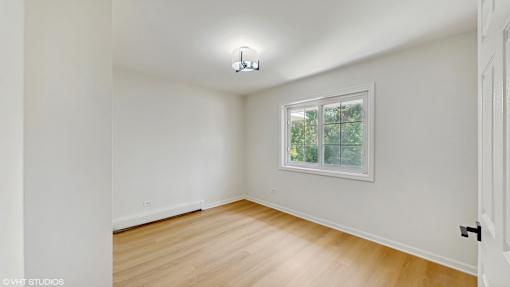 A room with a window and a wooden floor.