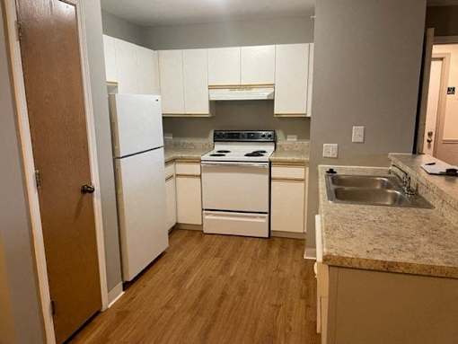 A kitchen with white appliances and wooden floors at Evergreen Luxury Apartments, Merrillville, Indiana, 46410