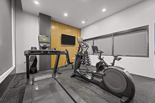 A treadmill and a stationary bike are in a room with a wooden panel wall.