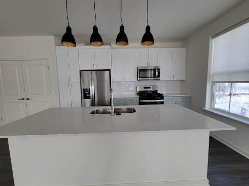 A kitchen with white cabinets and a large island.