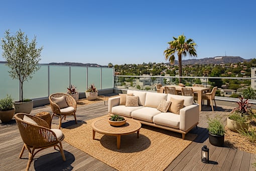 A private patio with a table and chairs overlooking a city at Fusion Hollywood Apartments.