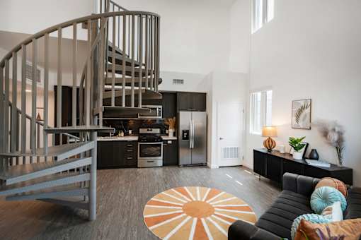 A modern living room with a spiral staircase and a black couch at Fusion Hollywood Apartments on Hollywood Blvd.
