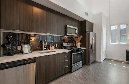 A modern kitchen with dark wood cabinets and stainless steel appliances at Fusion Hollywood Apartments