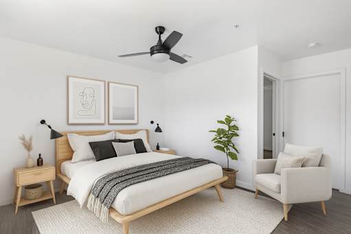 A bedroom with a bed, chair, and ceiling fan at Fusion Hollywood luxury Apartments.
