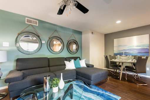 An apartment living room with a grey sofa, a glass coffee table, and a dining table with chairs at 1601 Eastchase Pkwy in Fort Worth, TX.
