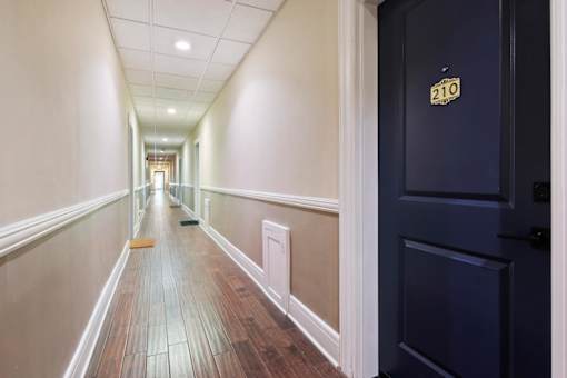 A hallway with a door on the right and a number 210 on the door.
