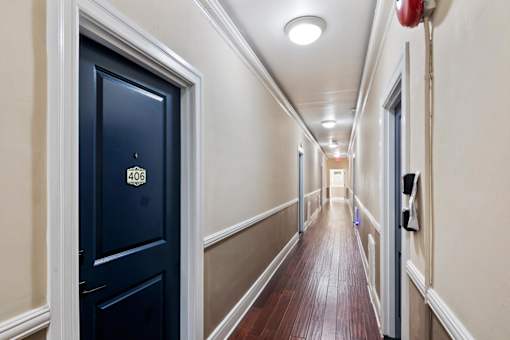 A hallway with a black door on the left and a red fire extinguisher on the right.
