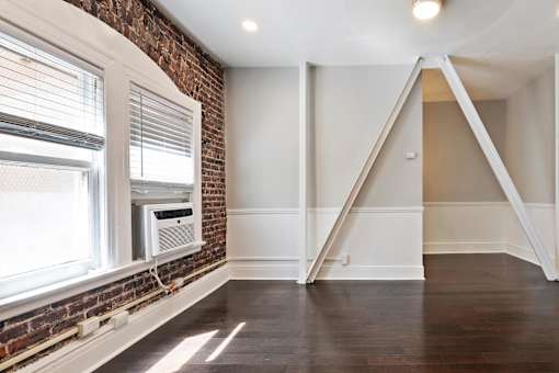An apartment with a brick wall and a window with blinds at Brookmore Pasadena apartments.
