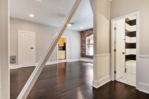 A studio apartment with a wooden floor and white walls at Brookmore Apartments in Pasadena, CA
