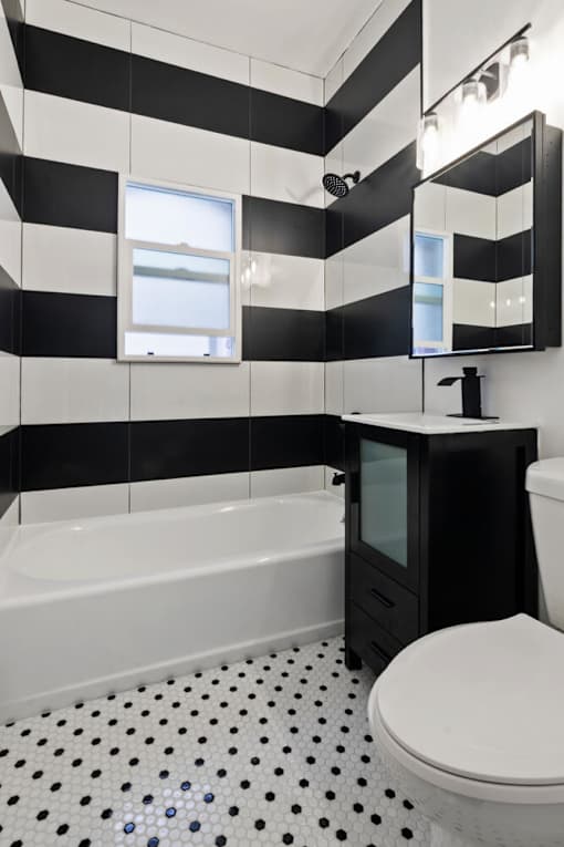 A black and white bathroom with a white toilet and a black cabinet at Brookmore Apartments Pasadena.