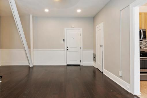 A room with a white door and a brown floor.