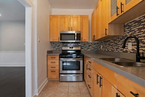 A kitchen with wooden cabinets and a stone backsplash at Brookmore Apartments Pasadena, CA