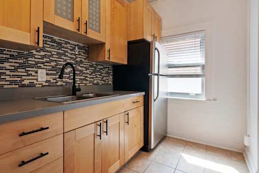 A kitchen with wooden cabinets and a black fridge.