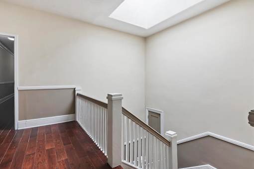 A landing with a wooden floor and a staircase with a railing.