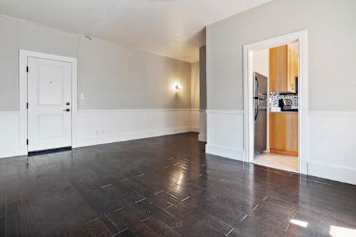 A studio apartment with a white door and a wooden floor at Brookmore.