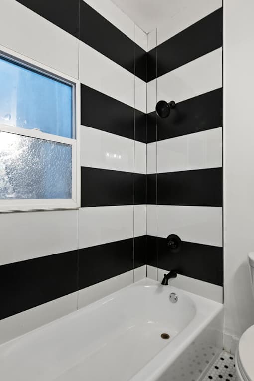 A black and white striped bathroom with a tub and toilet at Brookmore.