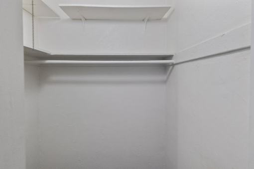 A white wall with a shelf and a door.