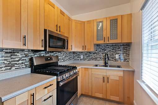 A kitchen with wooden cabinets and a black stove top oven at Brookmore Pasadena, CA apartments.