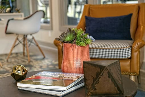 The Retreat at Indian Lake apts lobby sitting area with mid-century modern chair next to coffee table with succulent arrangement.