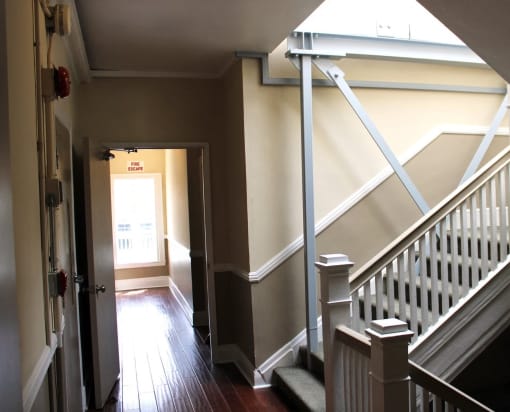 Pasadena Brookmore apartments stairwell with carpeted stairs, dual tone walls in dark and light tan with white trim, and dark wood inspired flooring