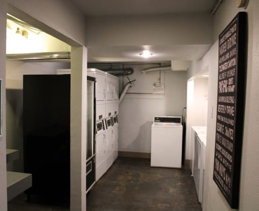 Pasadena Brookmore apartments on site laundry room with eight washers and dryers and a black vending machine on concrete floors