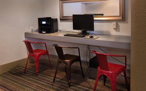 Brookmore Pasadena apartments computer lounge with wifi, a dell computer, and printer set up on a counter with two red stools and one black stool.